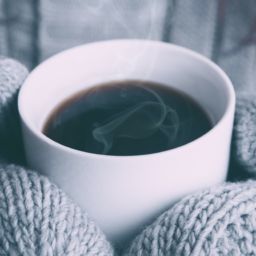 Gloved hands holding hot coffee