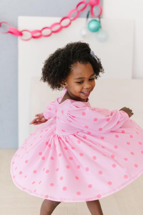 young girl twirling in a pink polka dot dress