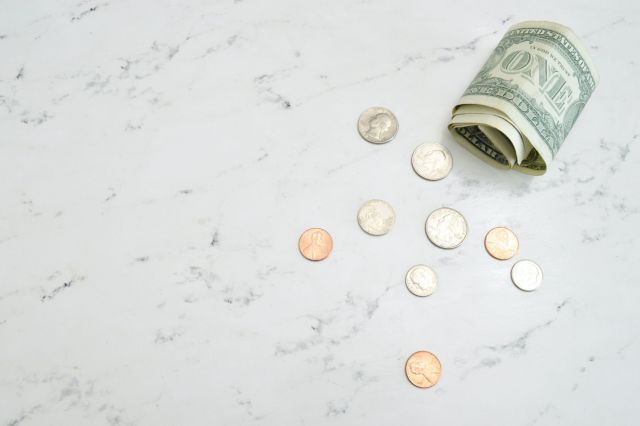 Rolled-up dollar bill and several coins on a marble counter