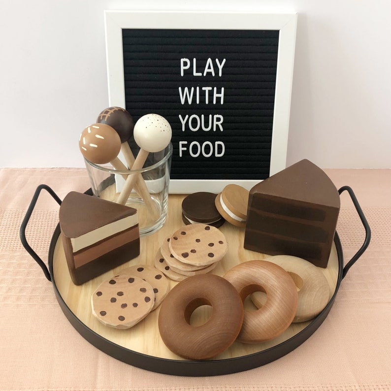 Wooden cake pops, cookles, donuts, cake slices and macarons from Sanded Sugar pictured with a sign that reads "Play with your food"