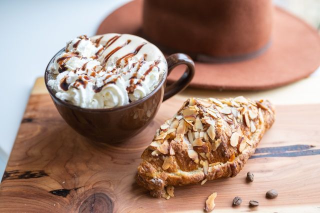 A mug of hot chocolate from Rose & Lois next to a croissant
