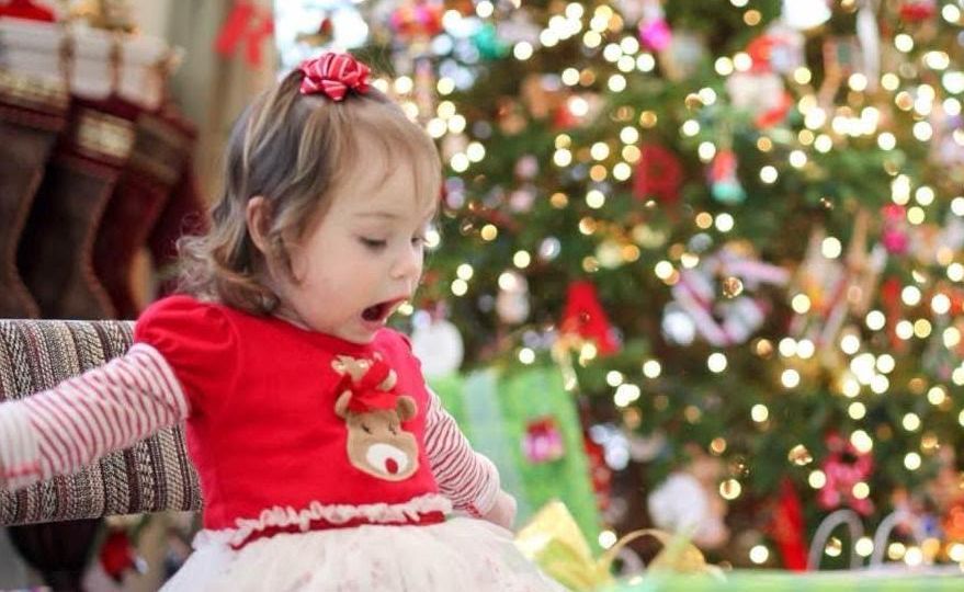 Girl surprised with joy opening a Christmas present
