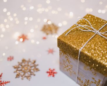 A gold package on a white background with colored snowflakes