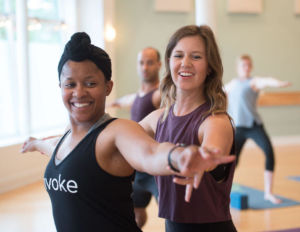 An instructor and student in a yoga class at Invoke Studio