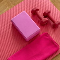 A photo of a yoga mat with a towel and hand weights