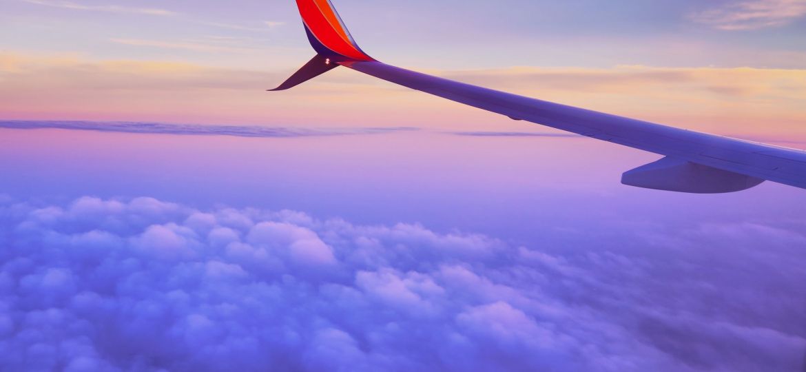 Tail of an airplane at sunset over purple clouds and sky