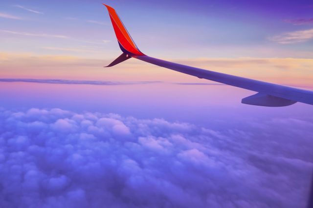 Tail of an airplane at sunset over purple clouds and sky