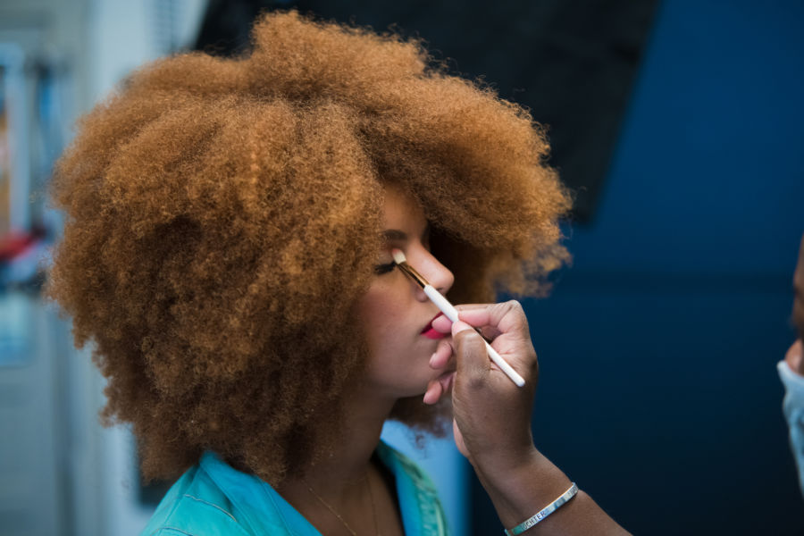 A photo of a model getting her makeup done