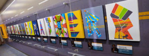 Various colorful artwork displayed behind a glass case. 