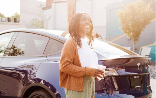 A woman standing in front of a car