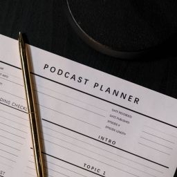 A photo of a podcast planner with a pen