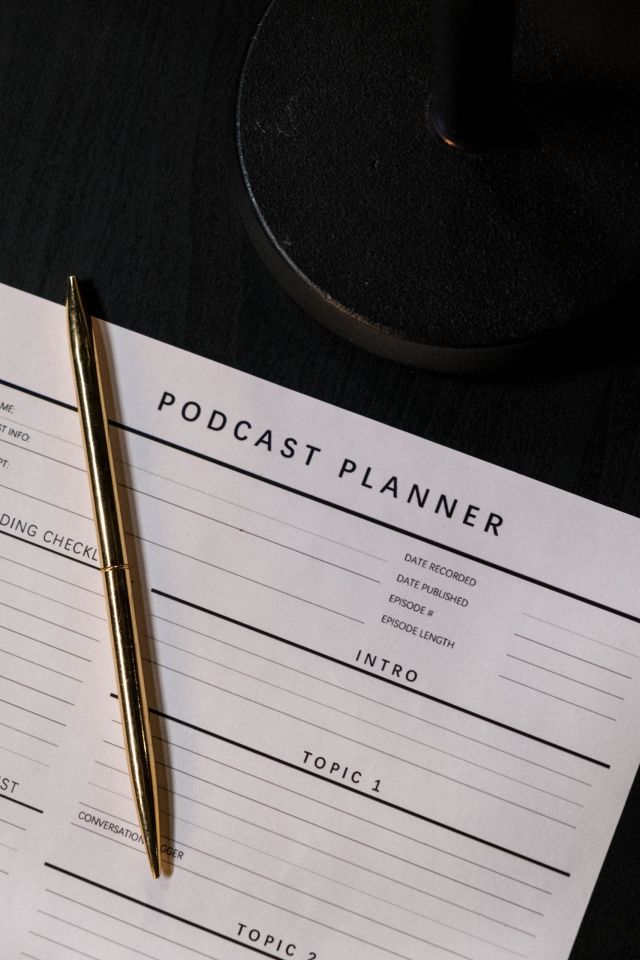 A photo of a podcast planner with a pen