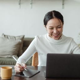 A smiling woman working on a laptop
