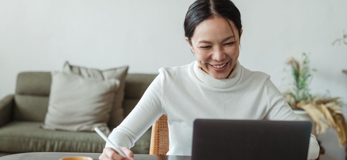 A smiling woman working on a laptop