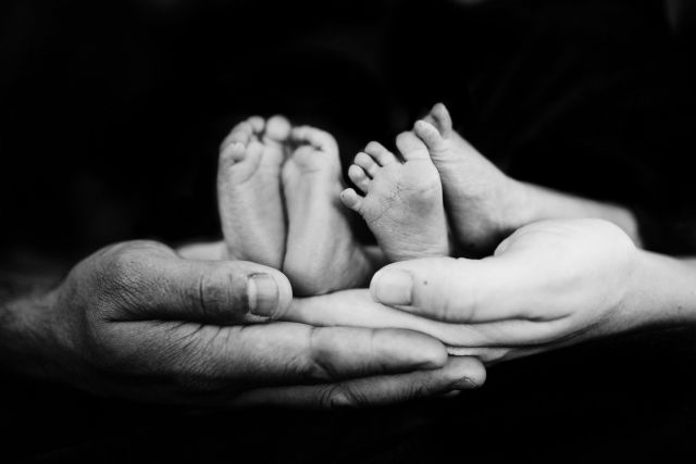 A photo of hands holding baby feet