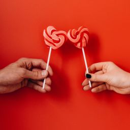 Romantic photo of two people holding lollipops