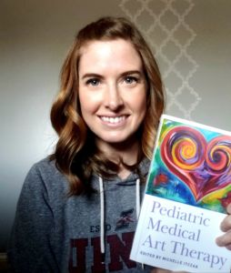 A photo of Michelle Itczak holding her book "Pediatric Medical Art Therapy"