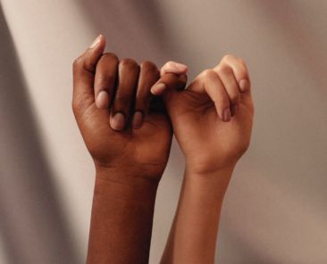 Two women linking fingers