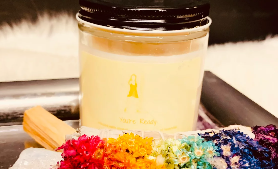 A photo of a candle next to colorful flowers