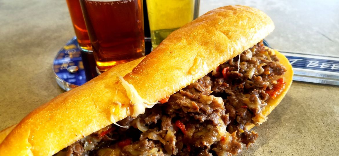 A photo of a cheesesteak with beer