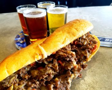 A photo of a cheesesteak with beer