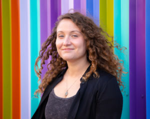 A photo of Kristen Bales standing in front of a colorful wall