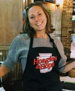 A photo of a woman in a Hoagies & Hops black apron