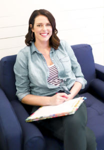 A photo of Lauren Reiker sitting with a clipboard