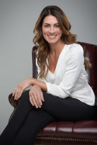 A photo of Lauren Schregardus sitting on a chair arms folded