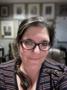 A photo of a woman in a braid with glasses and a striped shirt