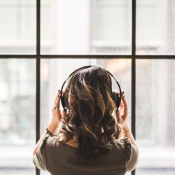 A photo of the back of a woman's head with headphones on