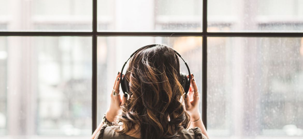 A photo of the back of a woman's head with headphones on
