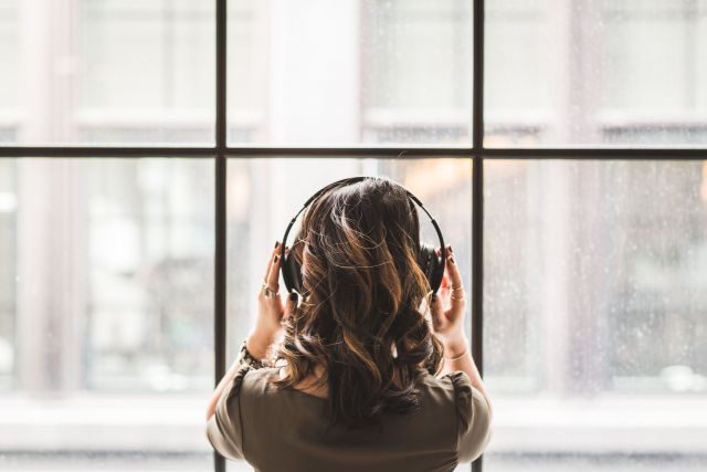 A photo of the back of a woman's head with headphones on