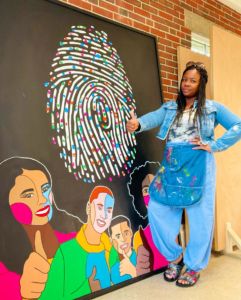 A photo of Shaunte Lewis next to a painting with a thumbprint