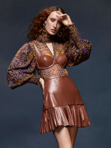 A model in a brown leather skirt and top with long sleeves and flowers