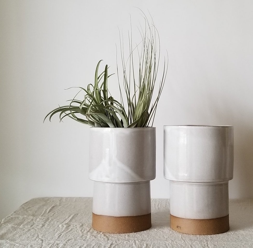 A photo of two planters that are both neutral colors