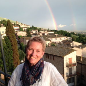 A photo of a woman standing with a rainbow behind her