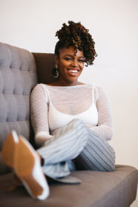 A photo of a woman sitting on a couch smiling