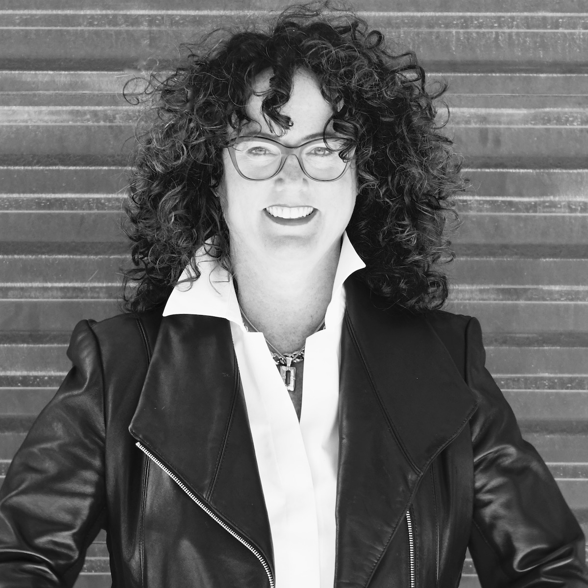 A black and white photo of a woman with dark curly hair and a leather jacket