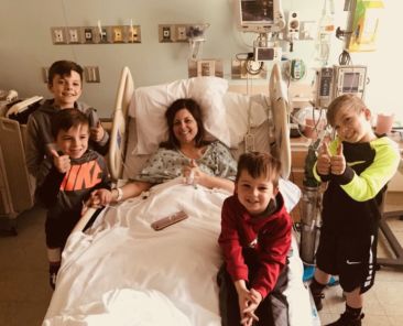 A photo of a woman in a hospital bed with all the kids