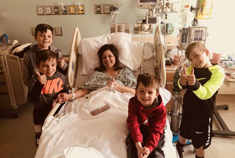A photo of a woman in a hospital bed with all the kids