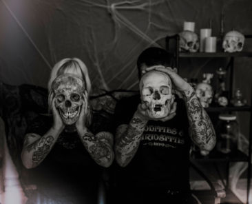 Two people holding skulls in front of their faces