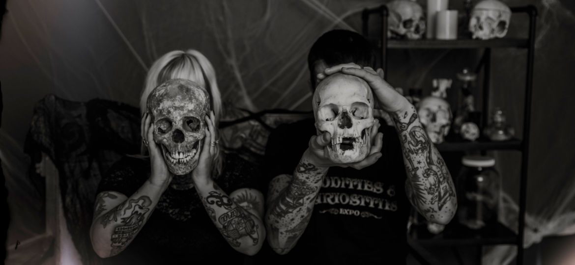Two people holding skulls in front of their faces