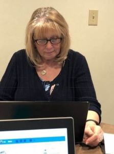A photo of a woman in glasses on a computer