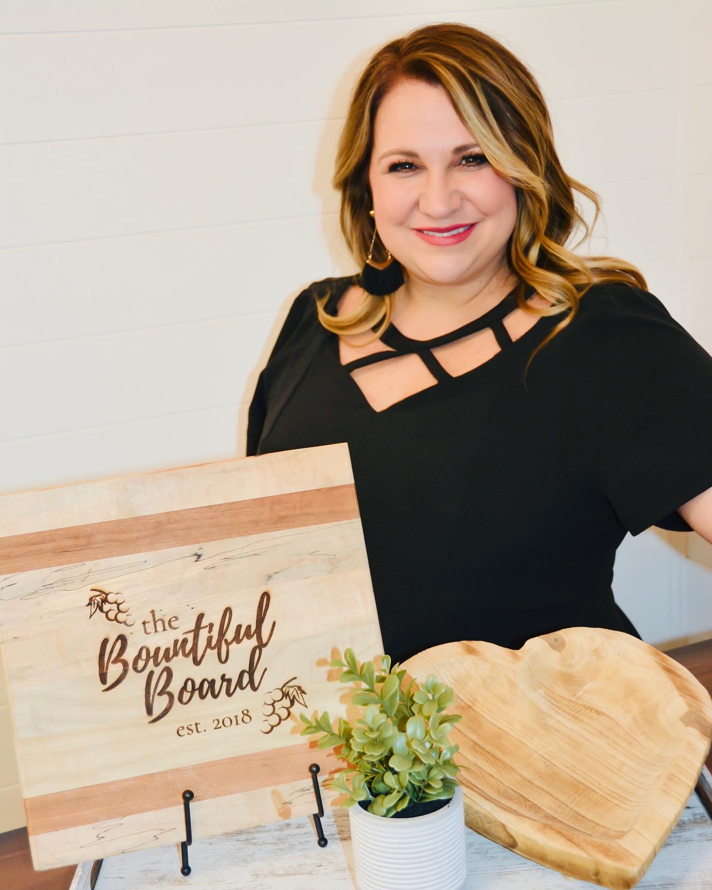 A photo of a woman smiling next to a sign that reads "the Beautiful Board"