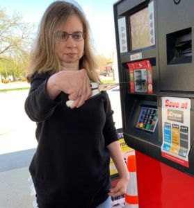 A photo of a woman using pliers at a gas station to be able to insert her card with arthritis