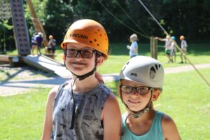 Two little girls who are camp riley campers are wearing glasses and helmets and smiling 