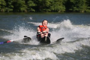 Female camper smiles and laughs as she slowly starts to fall off the water ski
