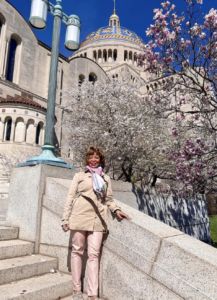 older woman poses and smiles in front of a historic building in Washington DC