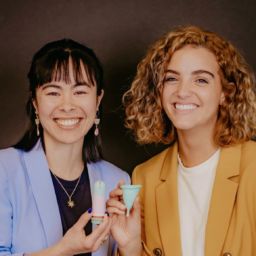 two women smiling holding reusable menstrual cups